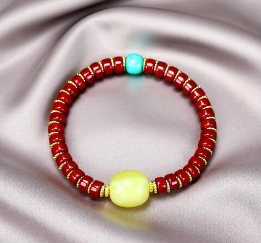 A bracelet made of Southern Red Agate pill beads, featuring a yellow amber main bead and turquoise accents, showcasing three colors.