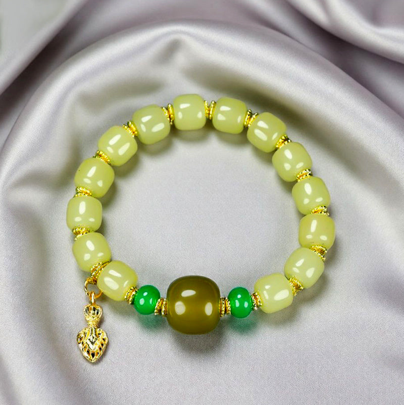 Yellow-green chalcedony barrel bead bracelet featuring gold spacers, a deep olive-green main bead, emerald-green small round beads, and a gold lotus-shaped charm.