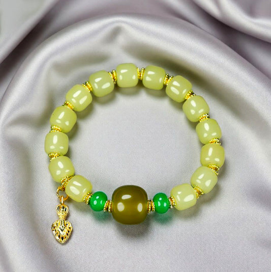 Yellow-green chalcedony barrel bead bracelet featuring gold spacers, a deep olive-green main bead, emerald-green small round beads, and a gold lotus-shaped charm.