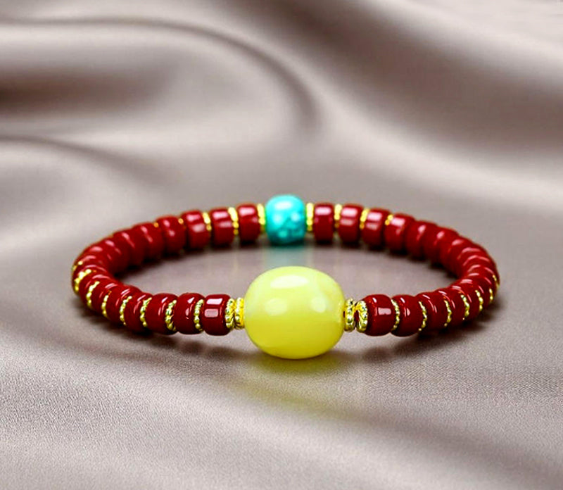 A bracelet made of Southern Red Agate pill beads, featuring a yellow amber main bead and turquoise accents, showcasing three colors.