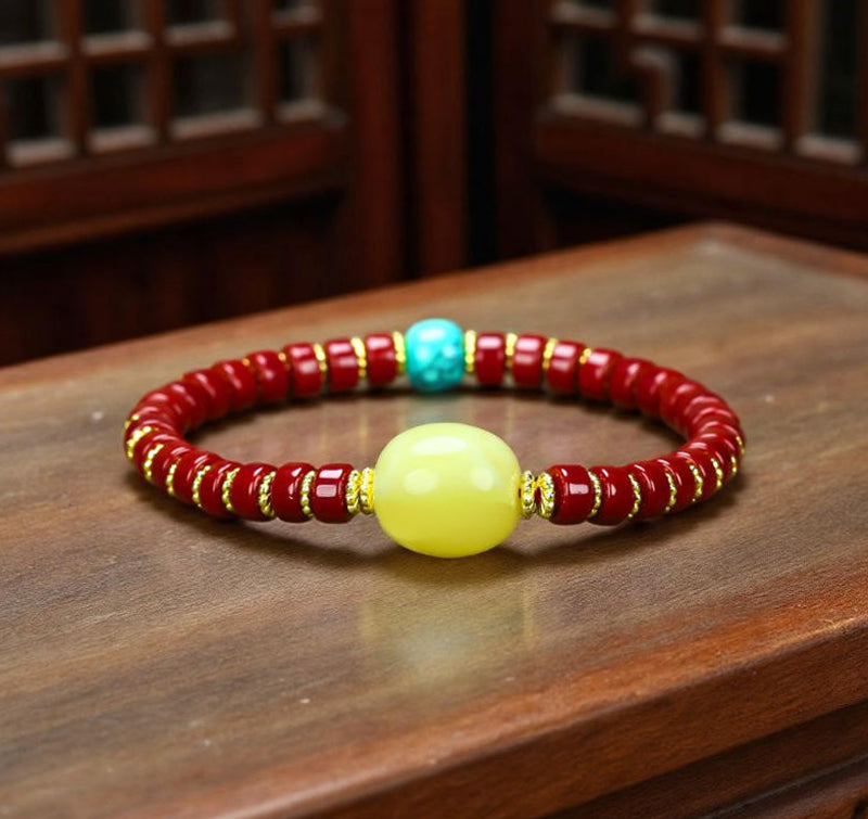 A bracelet made of Southern Red Agate pill beads, featuring a yellow amber main bead and turquoise accents, showcasing three colors.