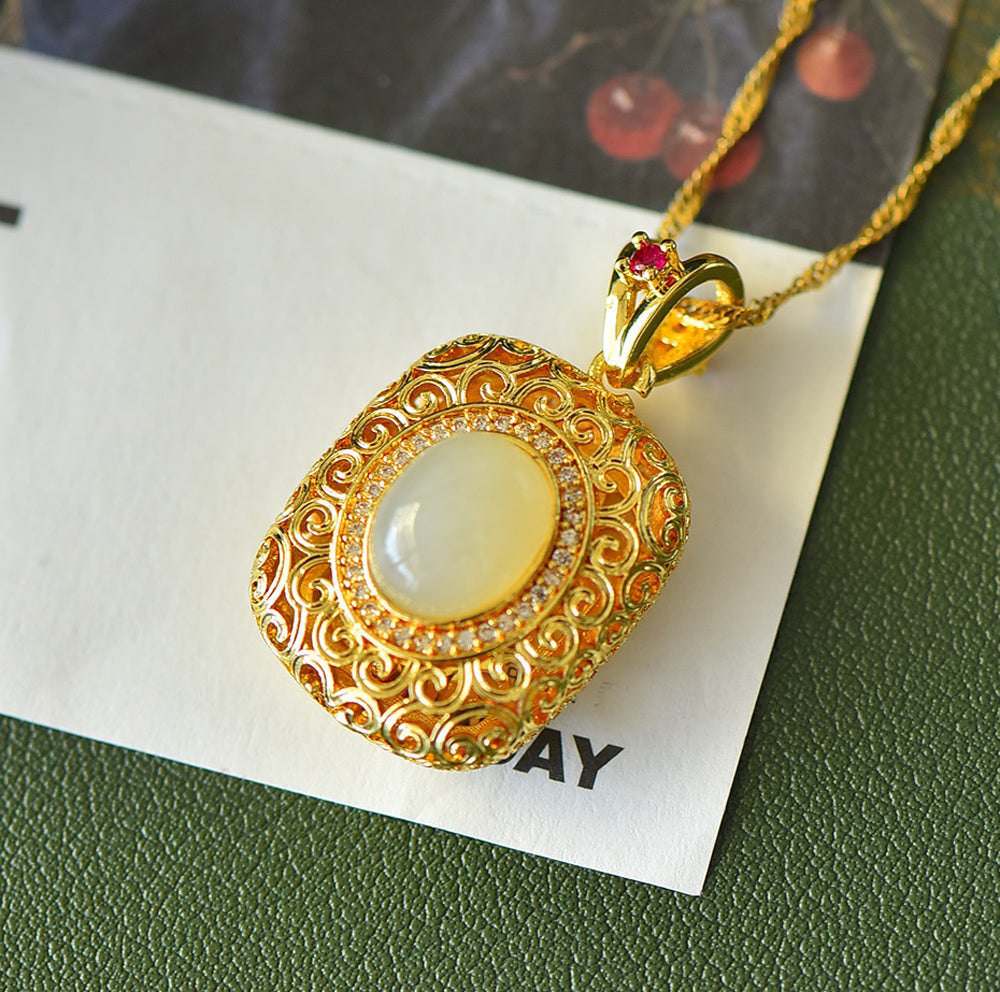 A necklace featuring a gold-tone pendant .Gold-Tone Openwork Scrollwork Box Pendant Necklace Embellished with Zircons, Luxurious & Elegant