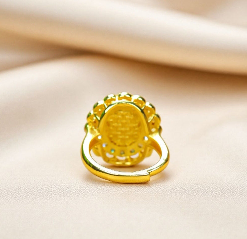 Emerald-green jade cabochon ring featuring a golden flower design; the golden petal-shaped setting is accented with inlaid zircon stones.