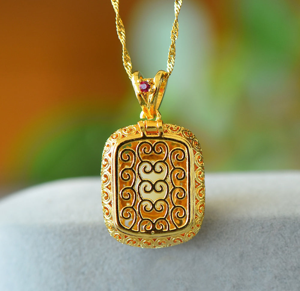 A necklace featuring a gold-tone pendant .Gold-Tone Openwork Scrollwork Box Pendant Necklace Embellished with Zircons, Luxurious & Elegant