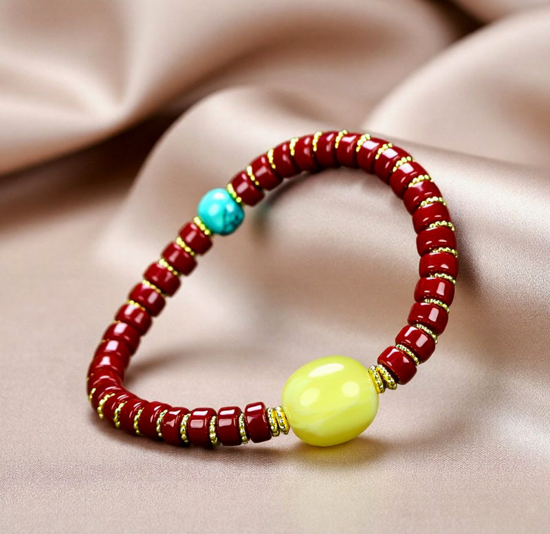A bracelet made of Southern Red Agate pill beads, featuring a yellow amber main bead and turquoise accents, showcasing three colors.