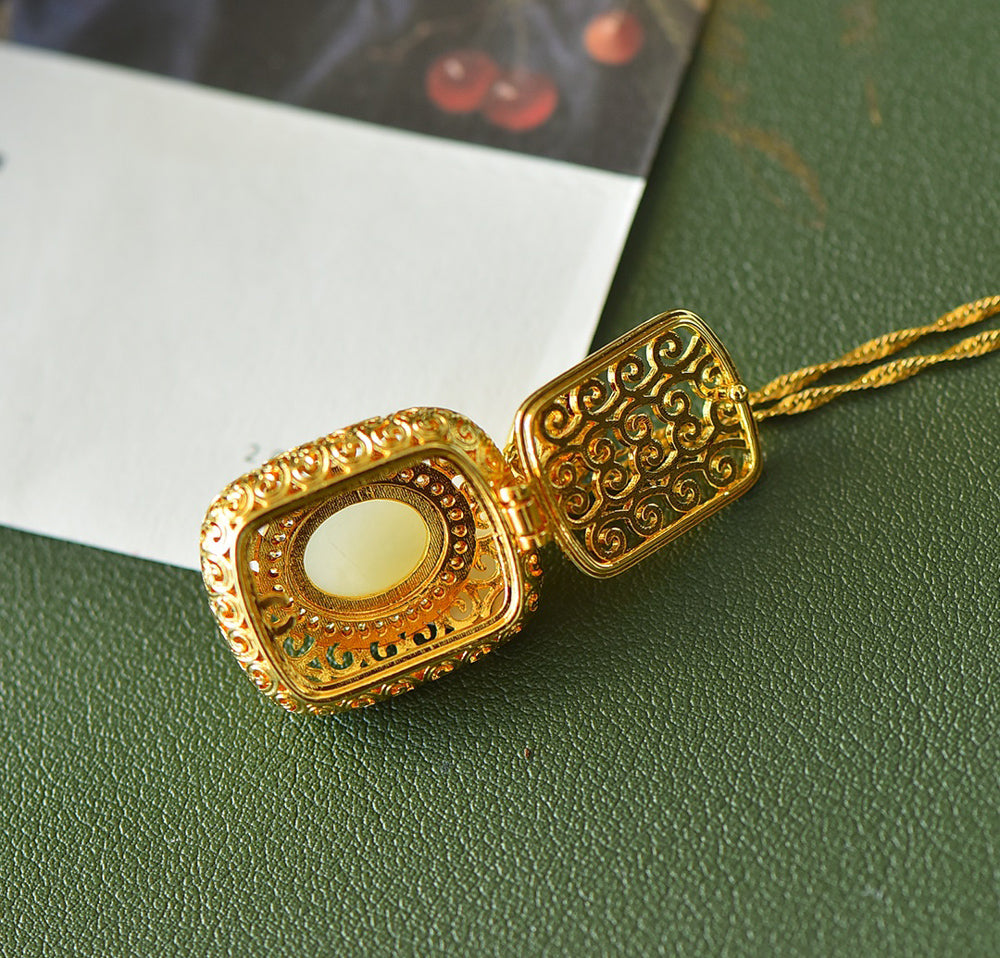 A necklace featuring a gold-tone pendant .Gold-Tone Openwork Scrollwork Box Pendant Necklace Embellished with Zircons, Luxurious & Elegant