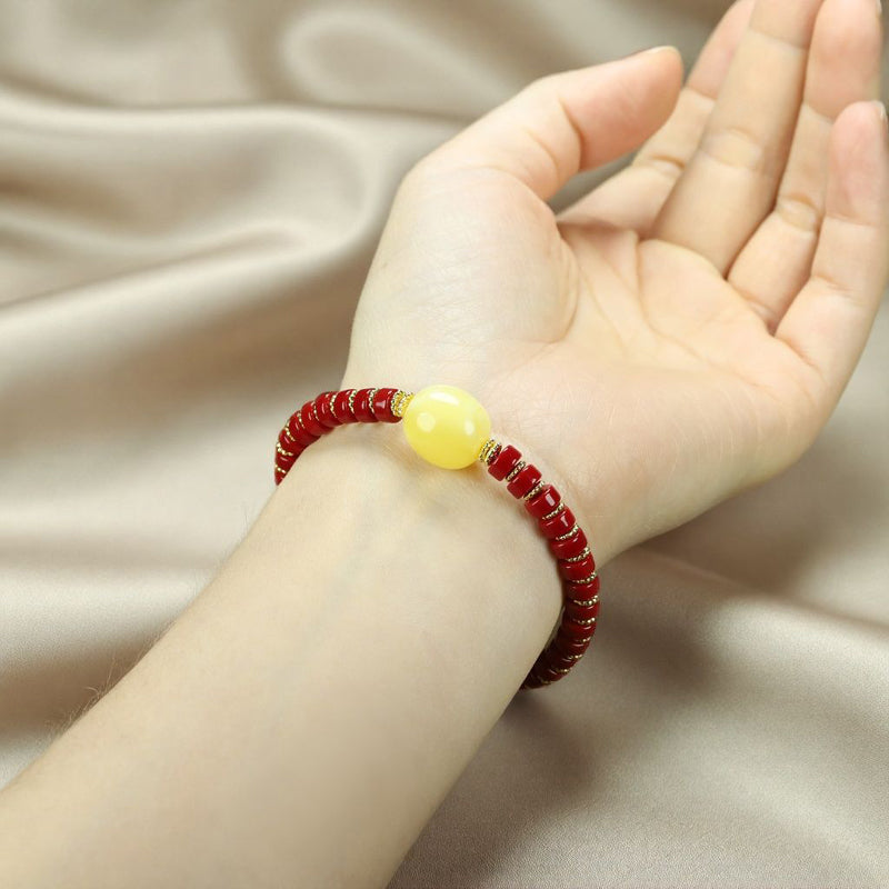 A bracelet made of Southern Red Agate pill beads, featuring a yellow amber main bead and turquoise accents, showcasing three colors.