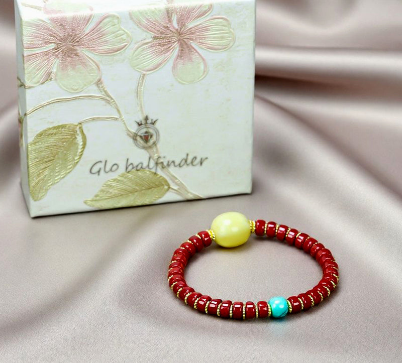 A bracelet made of Southern Red Agate pill beads, featuring a yellow amber main bead and turquoise accents, showcasing three colors.